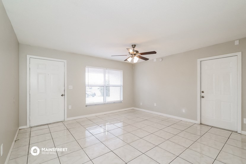 the living room of an empty home with a ceiling fan