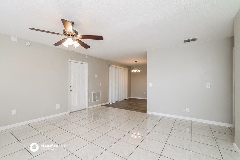 an empty living room with a ceiling fan and tiled floor