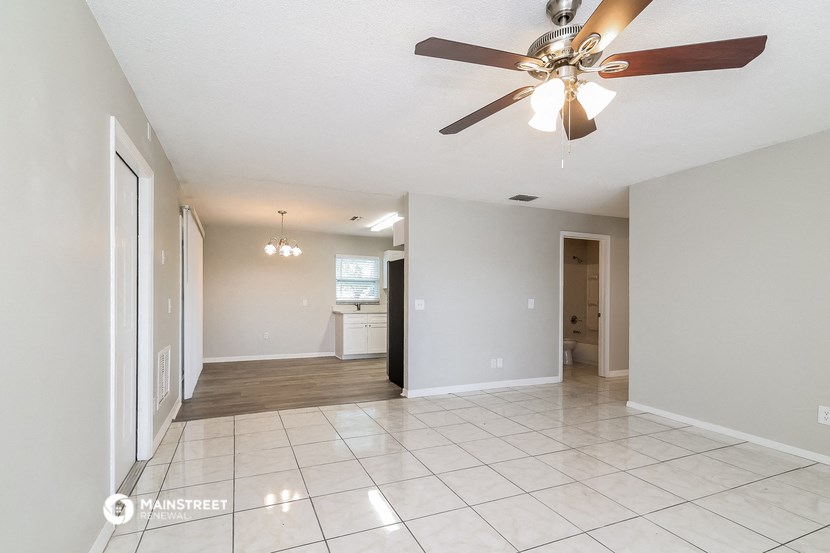 an empty living room with a ceiling fan and a tiled floor