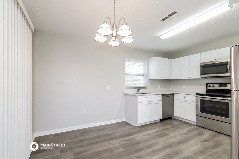 an empty kitchen with white cabinets and stainless steel appliances