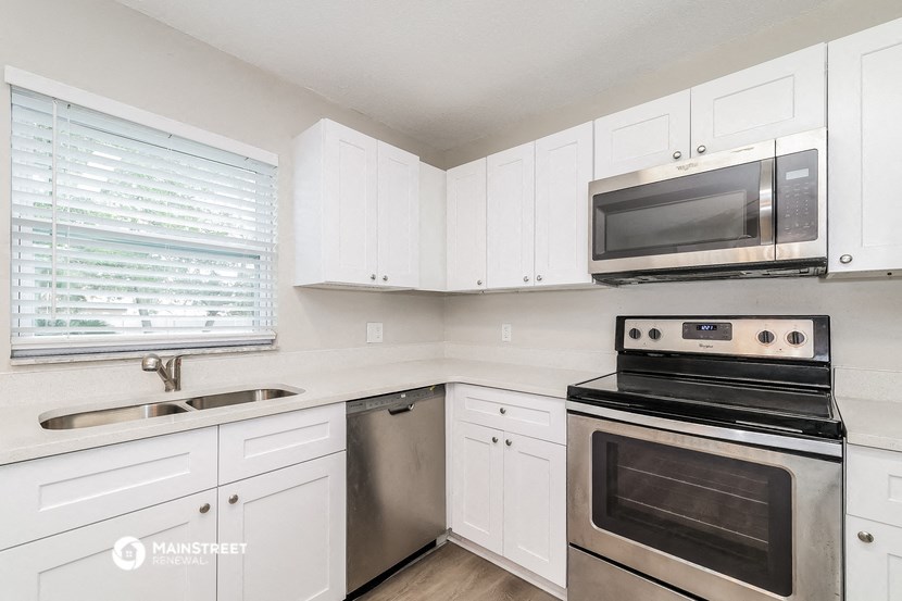 a white kitchen with stainless steel appliances and white cabinets