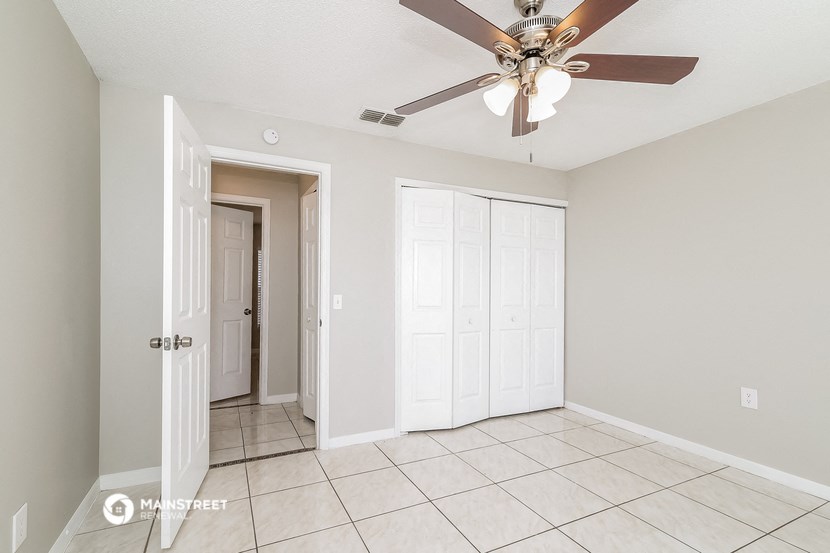 the living room of an empty home with a ceiling fan
