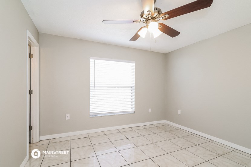 an empty room with a ceiling fan and a tiled floor