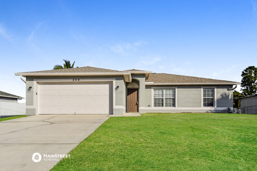 a beige house with a garage door and a lawn