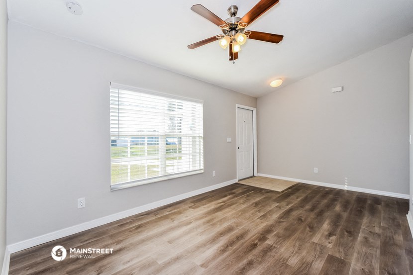 the spacious living room with a large window and a ceiling fan