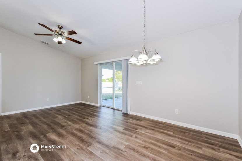 the spacious living room with wood flooring and ceiling fan