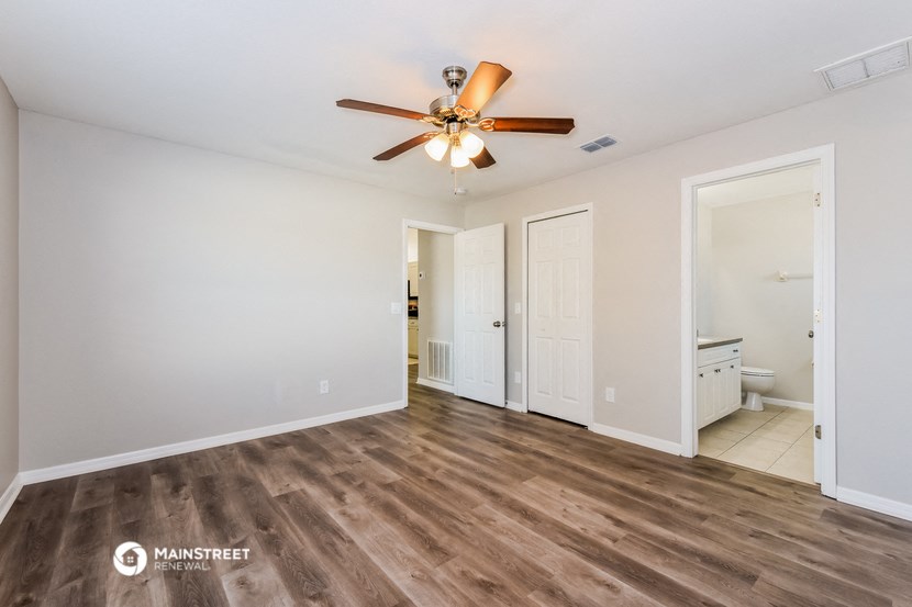 a living room with a ceiling fan and a door to a bathroom