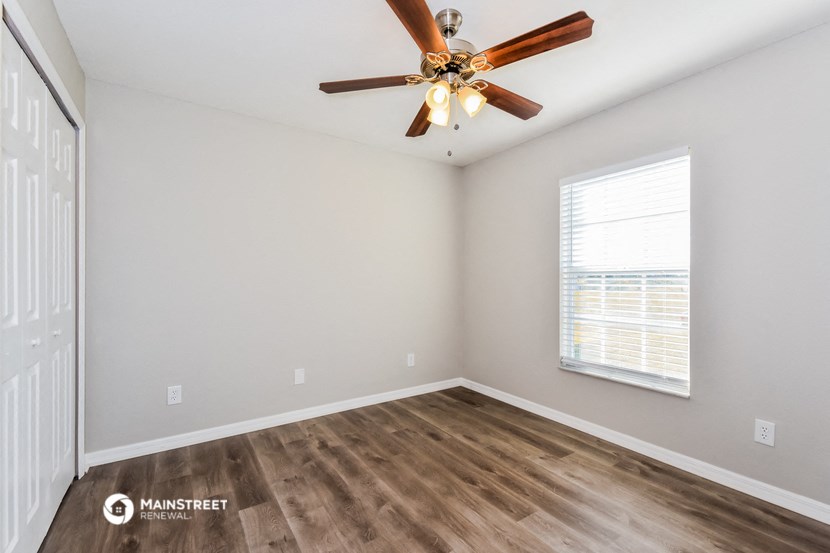 the spacious living room with wood flooring and a ceiling fan