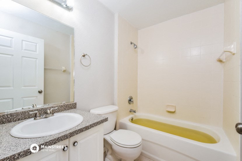 a white bathroom with a yellow tub and a sink and a toilet