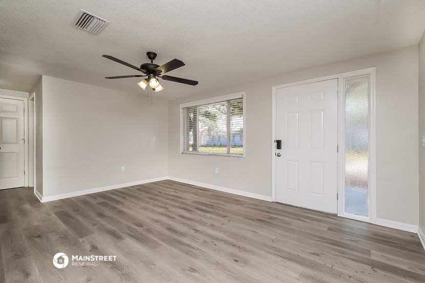 the living room of an empty house with a ceiling fan