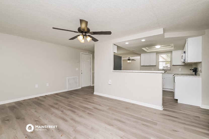 a living room with a ceiling fan and a kitchen