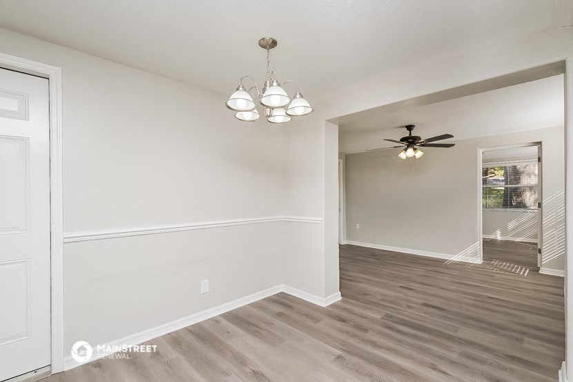 the spacious living room and dining room with white walls and a ceiling fan