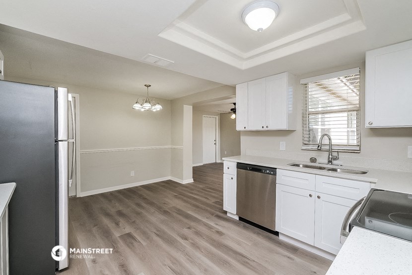 a kitchen with white cabinets and a stainless steel refrigerator