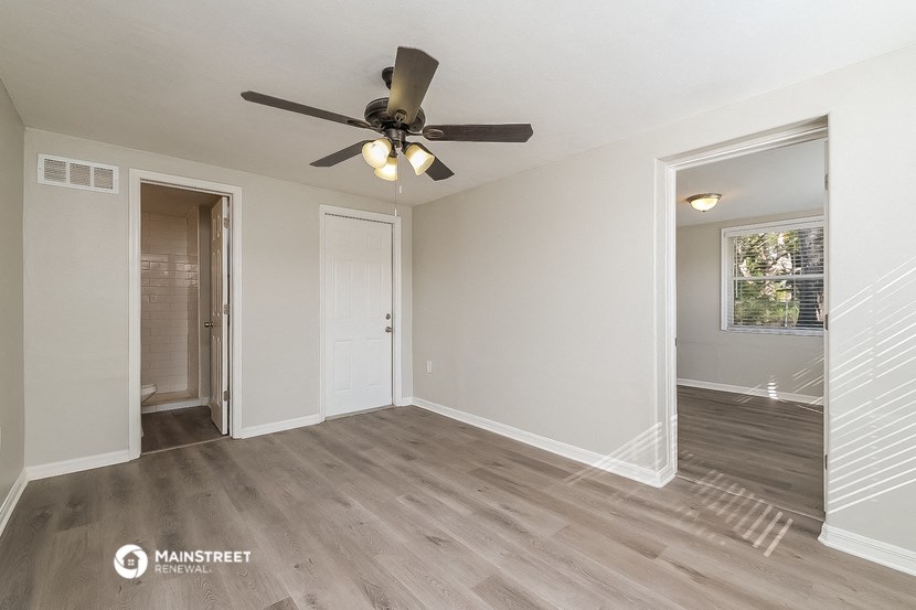a living room with a ceiling fan and a door to a hallway