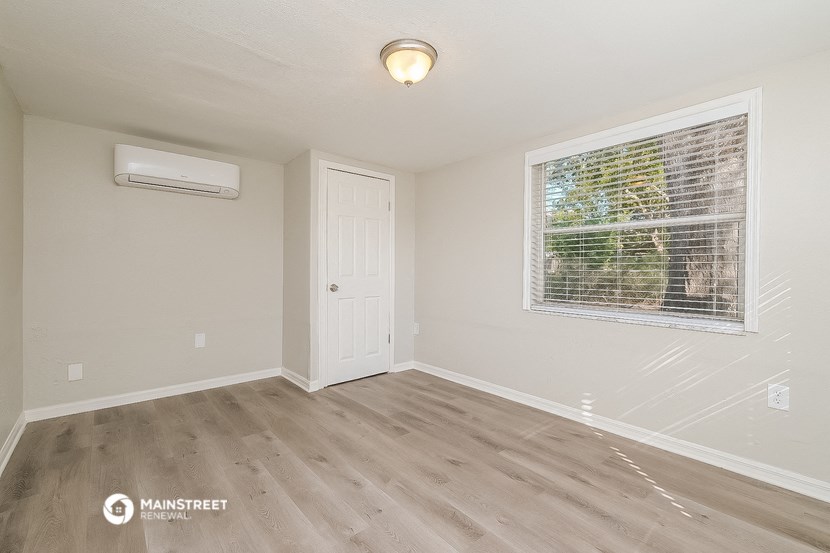 the living room of a small white house with a large window and a white door