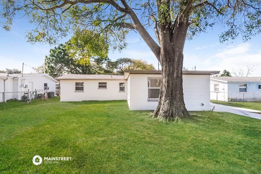 a white mobile home in a yard with a tree