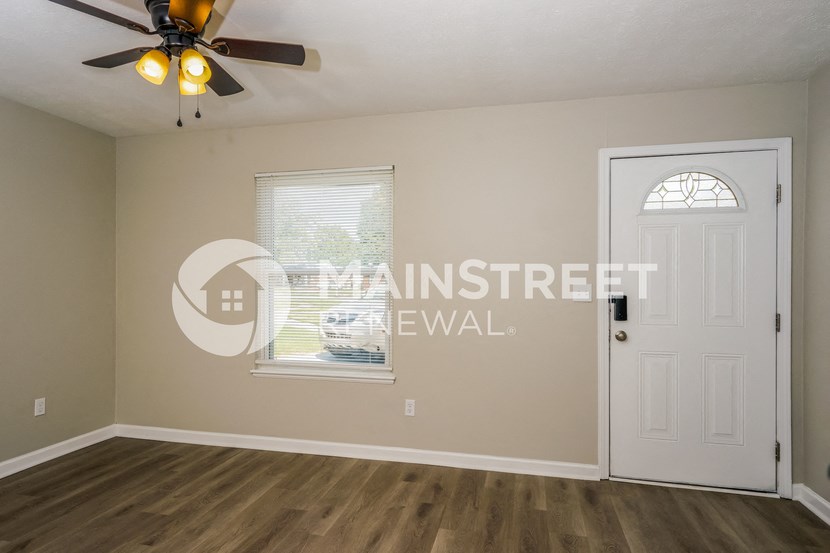 a living room with a white door and a ceiling fan