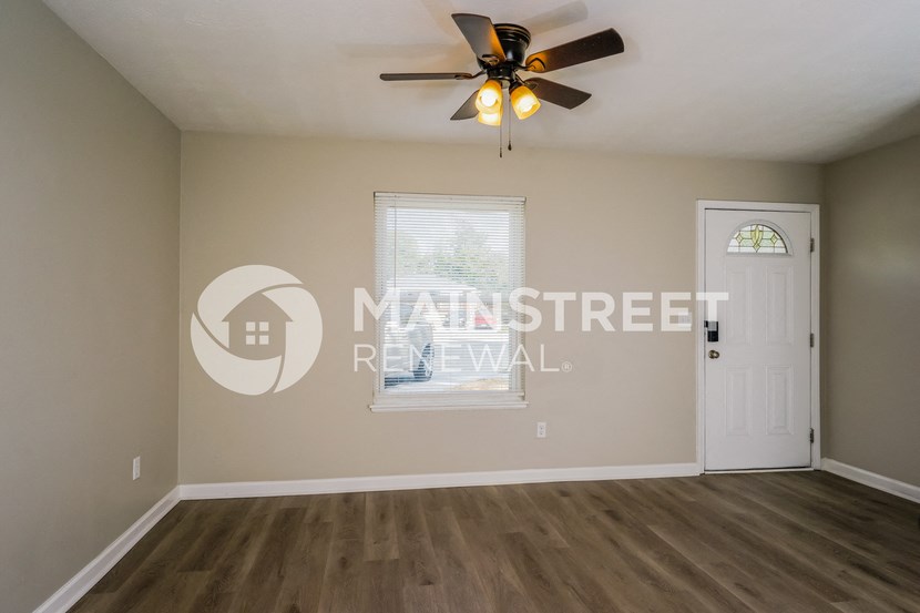an empty living room with a ceiling fan and a window