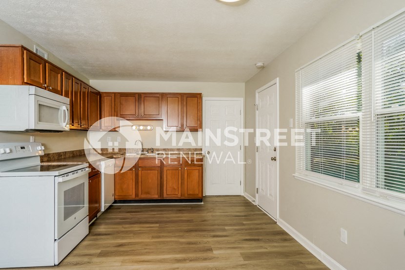 a kitchen with wood cabinets and white appliances and a large window