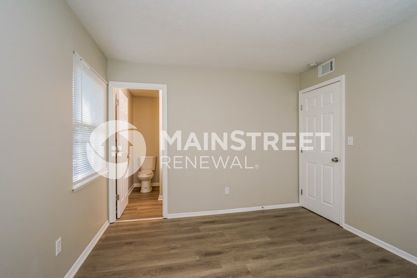 a bedroom with a door to the bathroom and a closet