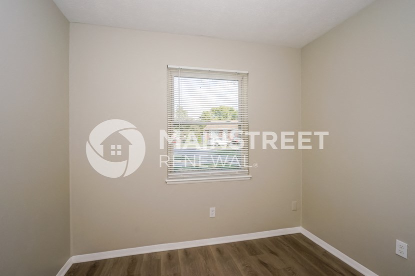a bedroom with a window and a wooden floor