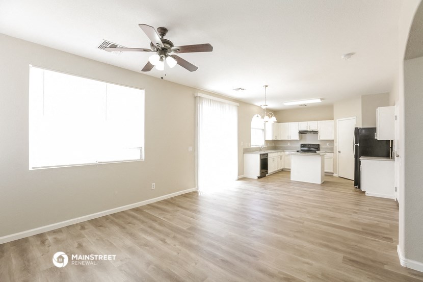an open kitchen and living room with wood flooring and a ceiling fan