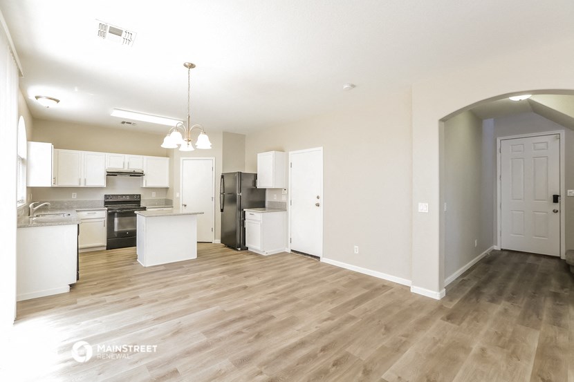 the living room and kitchen of an apartment with wood flooring