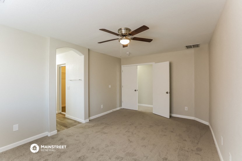 an empty living room with a ceiling fan