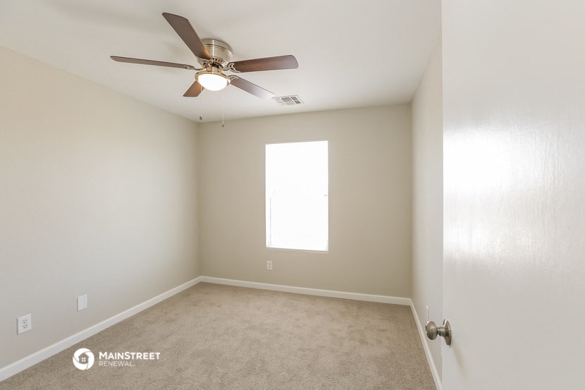 an empty room with a ceiling fan and a window