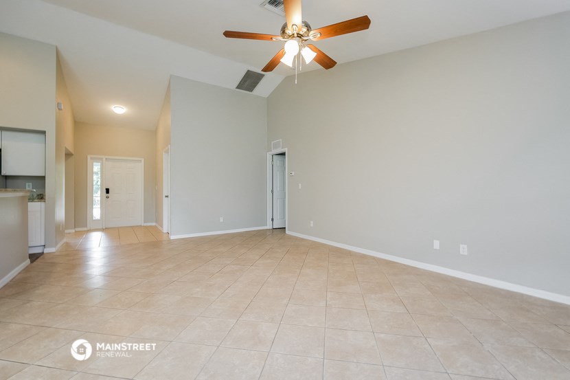 the spacious living room with ceiling fan and tile flooring