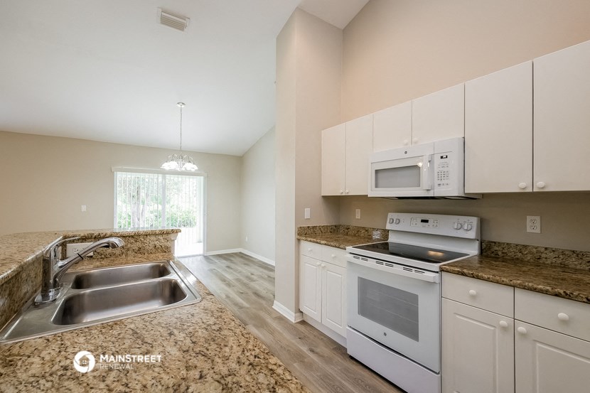 a kitchen with white appliances and granite counter tops and white cabinets