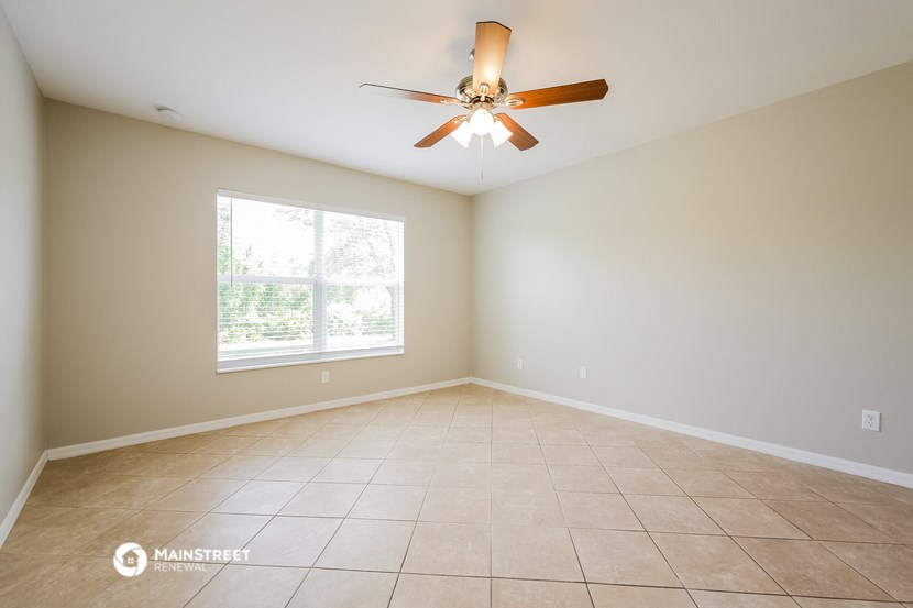 an empty living room with a ceiling fan and a window