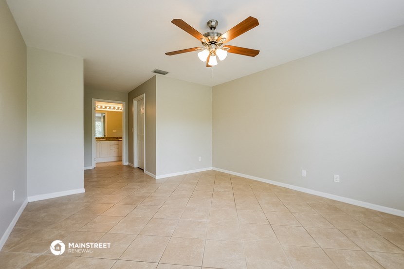 the spacious living room with ceiling fan and tile flooring