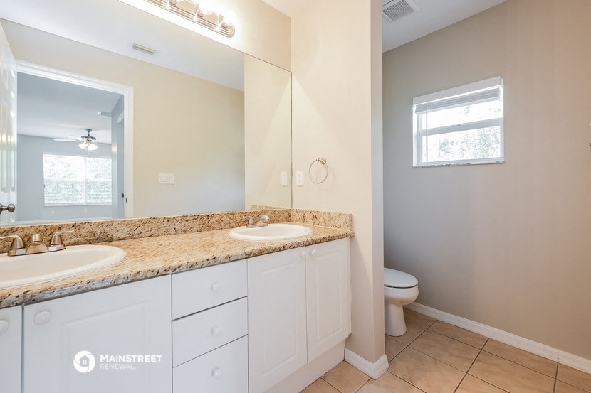 a bathroom with two sinks and a toilet and a large mirror