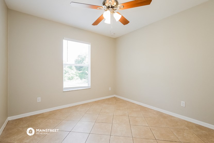 an empty living room with a ceiling fan and a window