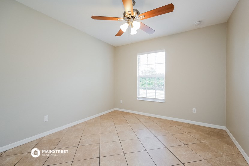 an empty living room with a ceiling fan and tiled floors