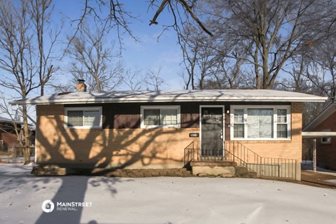 the front of a house with the shadows of trees on it