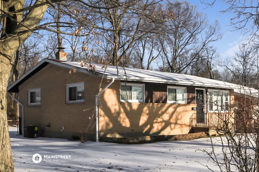 a small brown house with a metal roof in the snow
