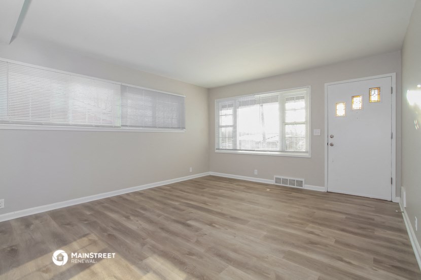the living room of an apartment with wood flooring and a white door