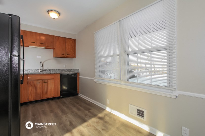 the kitchen of an apartment with wood flooring and a large window