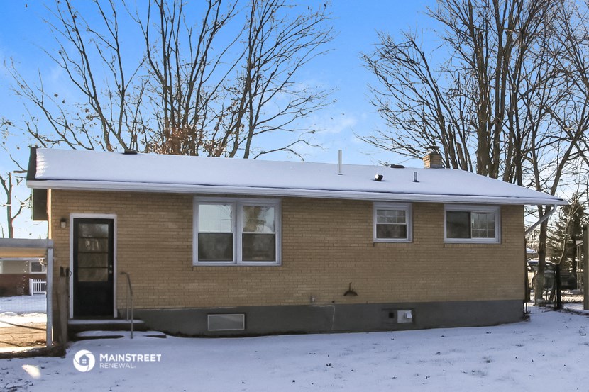a small brick house with snow on the roof