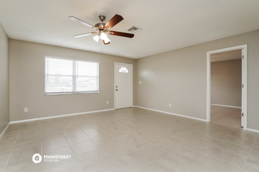the spacious living room with ceiling fan and tile flooring