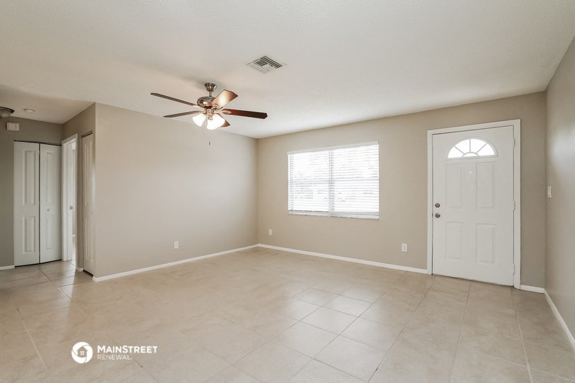 the spacious living room with ceiling fan and tiled floor
