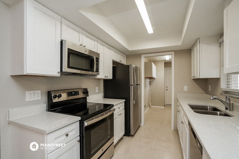 a kitchen with white cabinets and black appliances