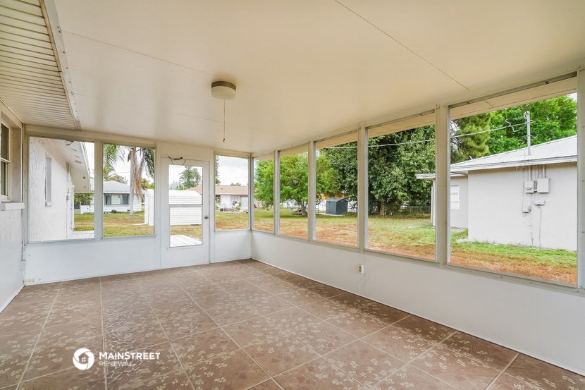 the living room of a house with large windows and a tiled floor