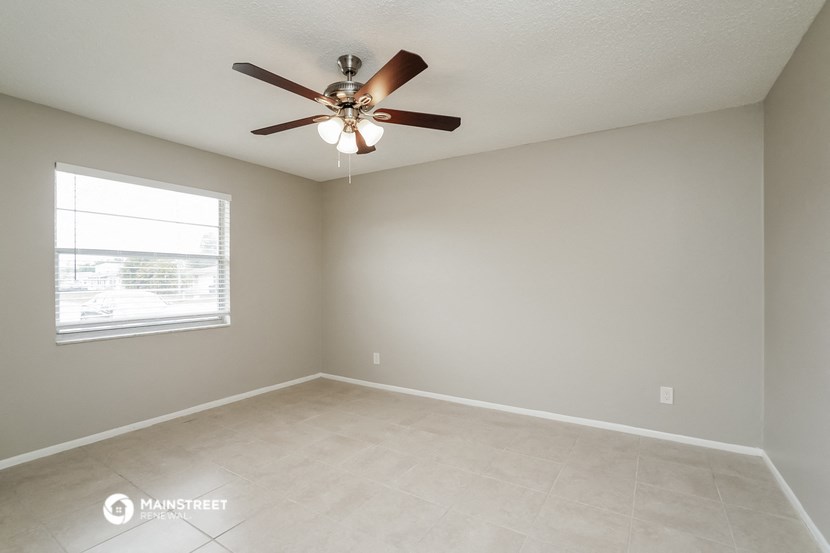 an empty living room with a ceiling fan and a window