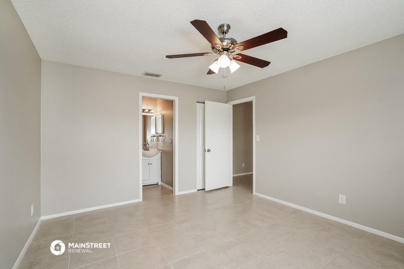 the spacious living room with ceiling fan and tile flooring