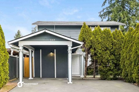 a blue house with a driveway and trees