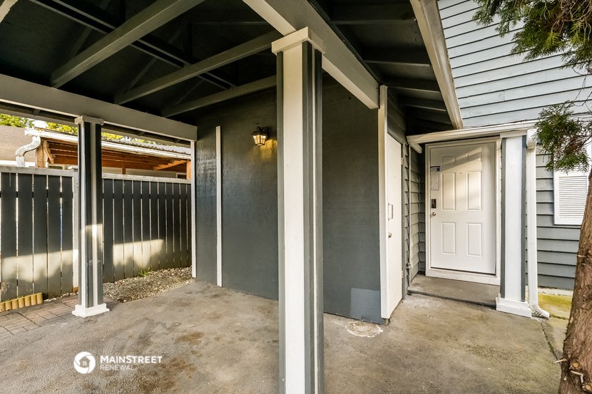 the entrance to a gray house with a white door