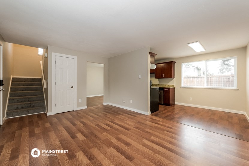the living room and kitchen of an apartment with wood flooring